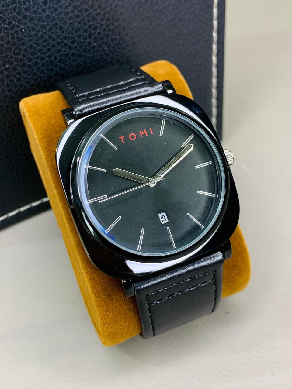 Front view of Tomy men's black analog watch with black leather strap and date display.