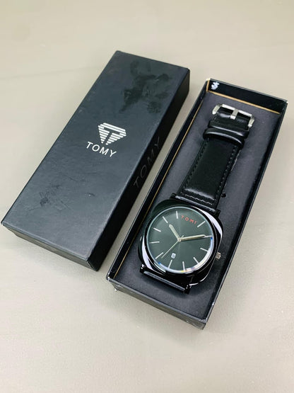 Tomy men's black leather analog watch displayed inside its premium gift box packaging.